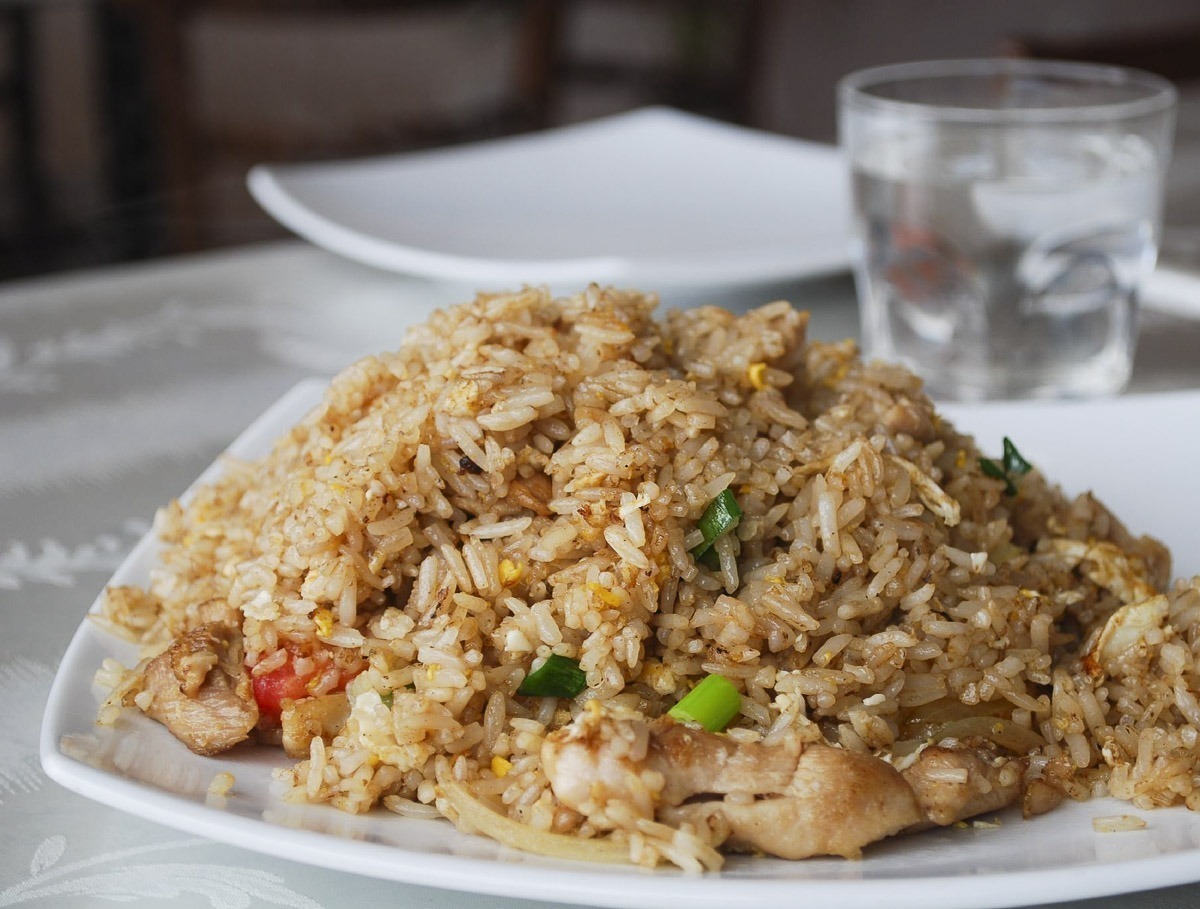 Prato de arroz frito tailandês com pedaços de frango, legumes e ovo.