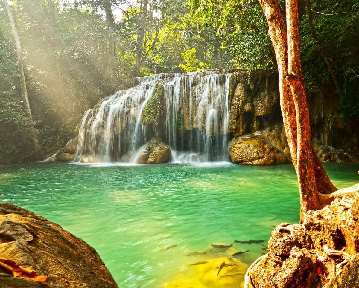 Queda d’água da cachoeira Erawan caindo em piscina natural verde-esmeralda em Kanchanaburi.