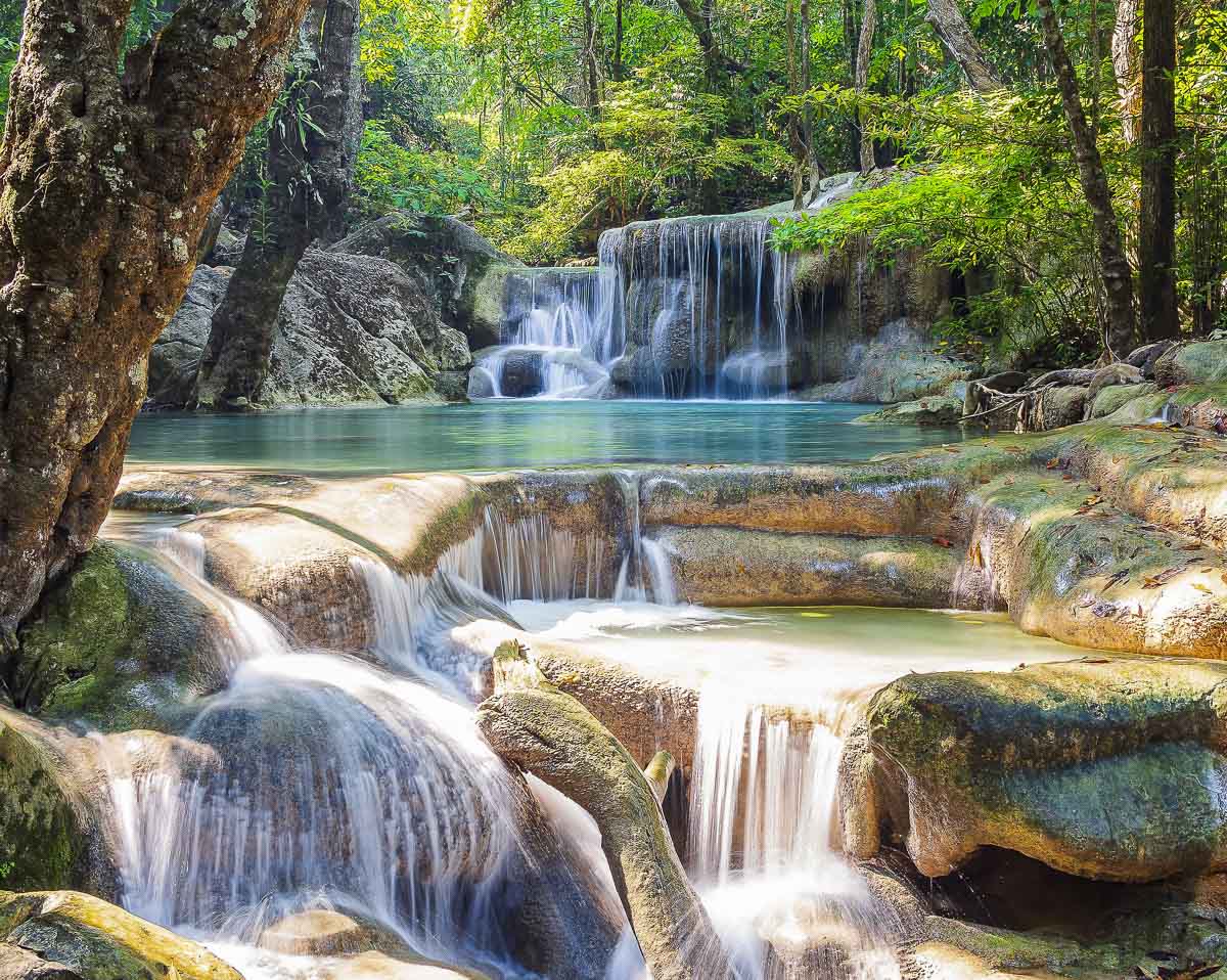 Vários níveis de pequenas quedas d’água cristalinas cercadas por floresta em Kanchanaburi.