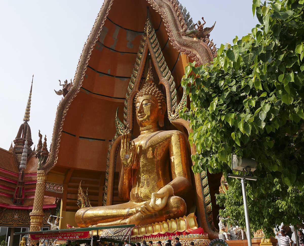 Estátua dourada gigante de Buda sentado em posição de bênção em templo em Kanchanaburi.