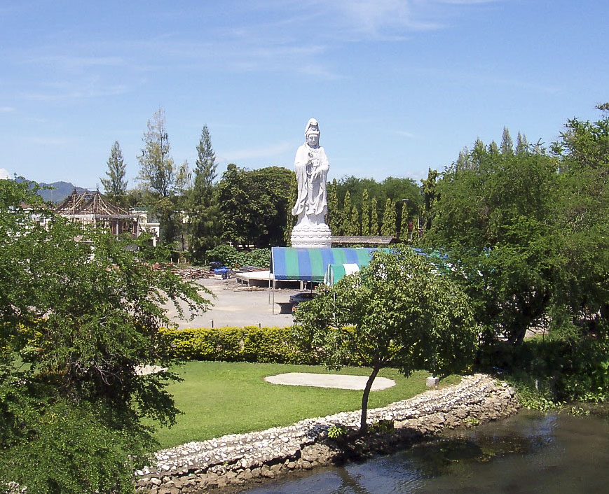 Estátua branca da deusa Kuan Yin no centro de um jardim em Kanchanaburi.