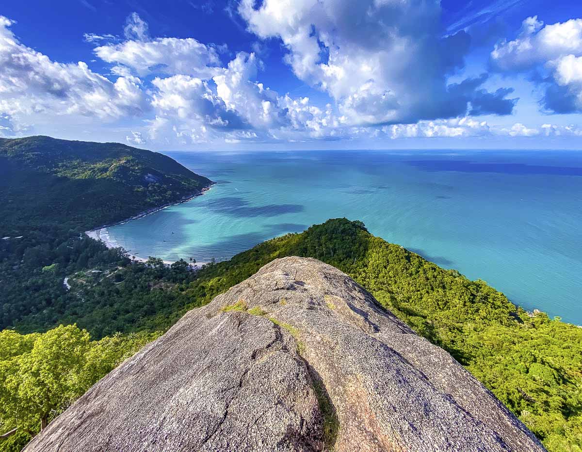 Vista do alto de uma montanha em Koh Phangan, com mar azul turquesa e colinas cobertas por floresta tropical.