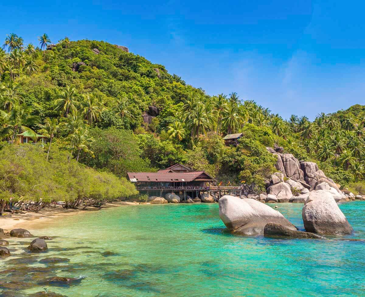 Margem rochosa de Koh Tao com mar transparente e vegetação tropical.