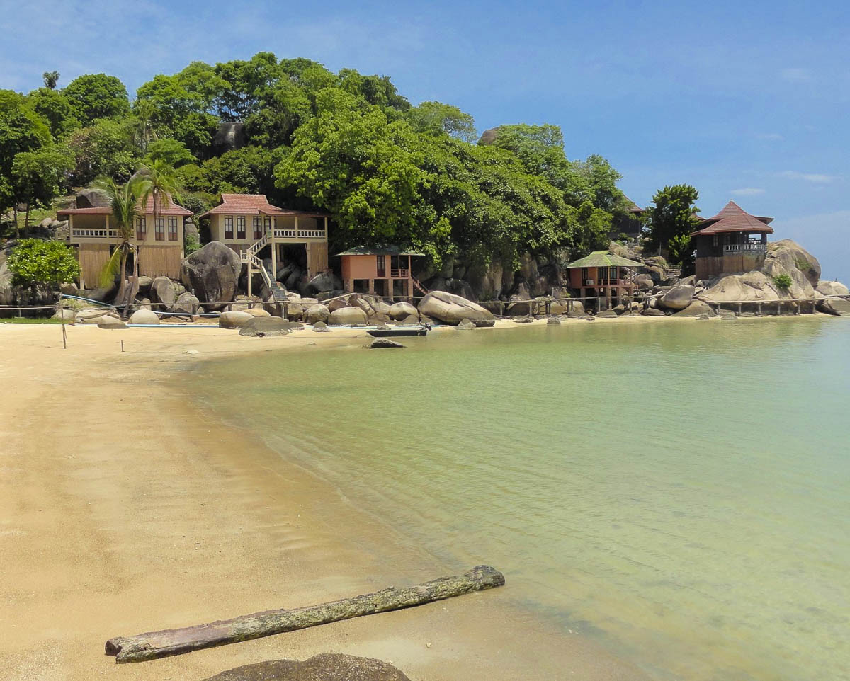 Bungalows de madeira construídos sobre pedras à beira do mar calmo em Koh Tao.