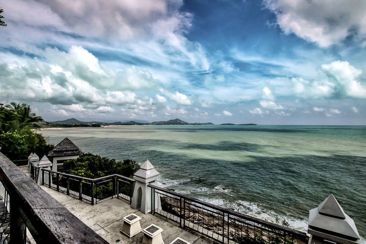 Um parapeito de ferro vista para o mar e montanhas ao fundo sob céu nublado em Koh Samui.