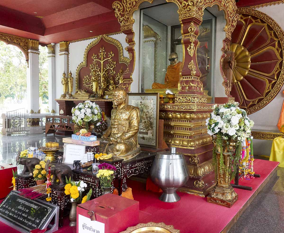 Altar budista com estátua dourada de monge e corpo mumificado em vitrine no Wat Khunaram, em Koh Samui.