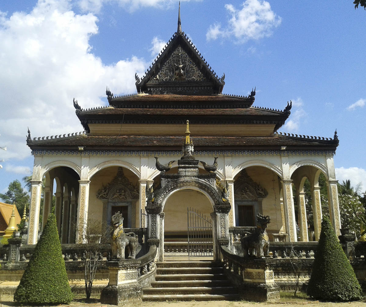 Fachada de templo tradicional budista com colunas, escadaria e esculturas decorativas.