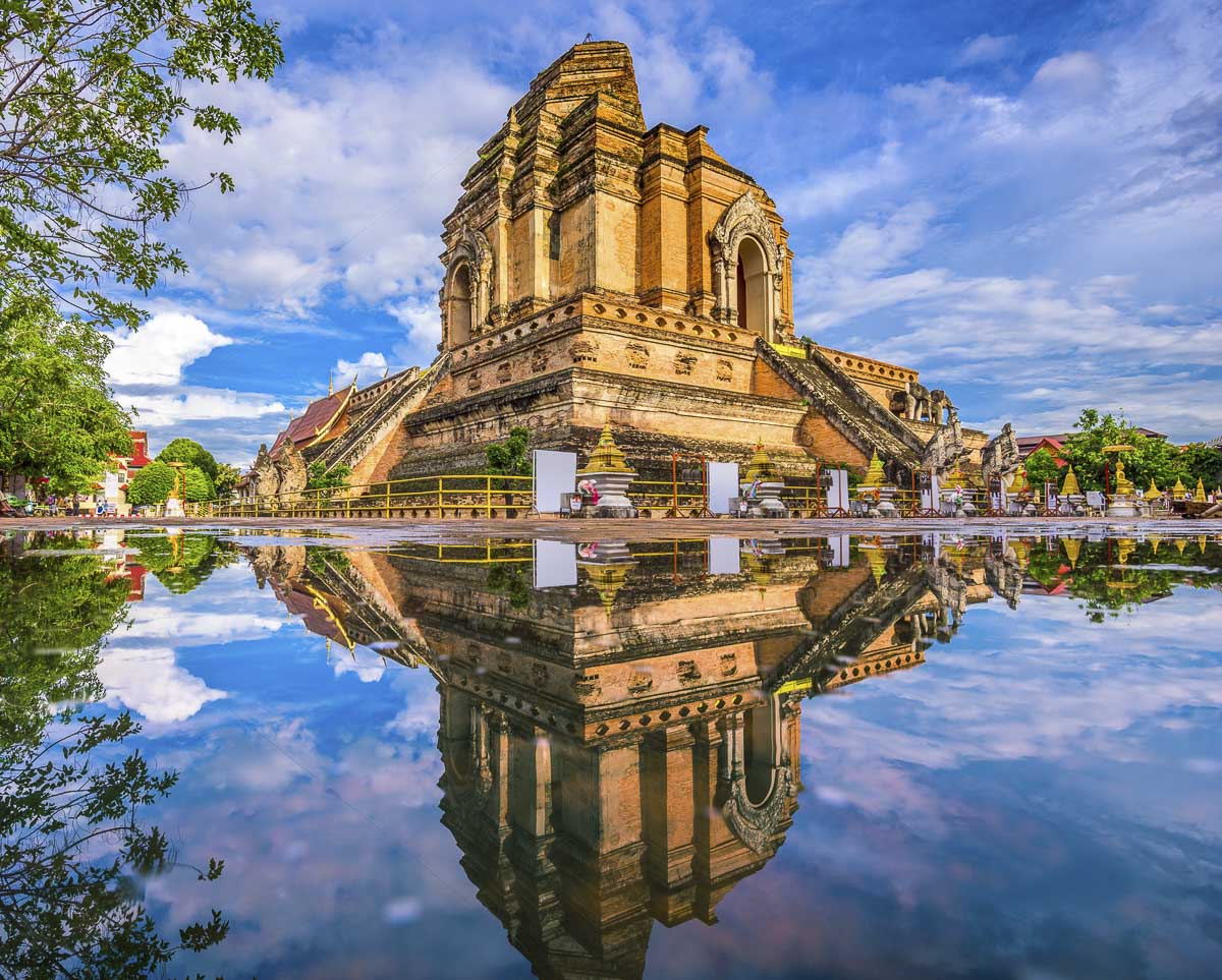 Estrutura antiga do templo Wat Chedi Luang refletida em uma superfície de água em Chiang Mai, Tailândia.