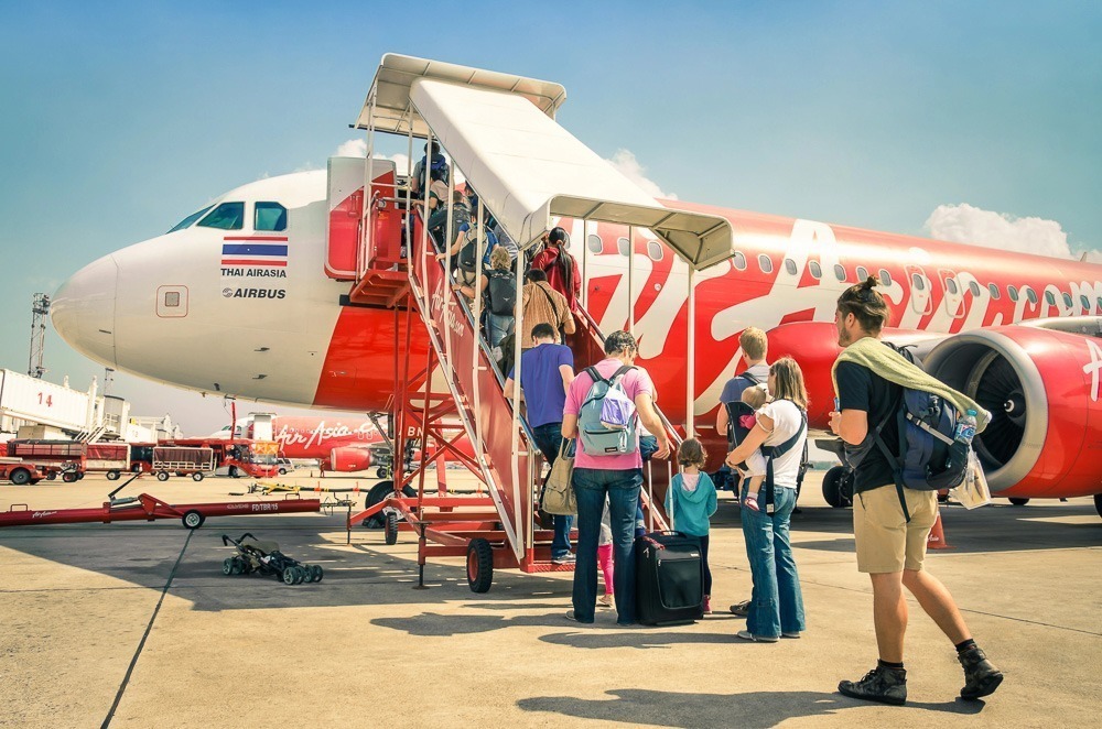 Um grupo de pessoas embarcam em um voo da Thai AirAsia no pátio do aeroporto.