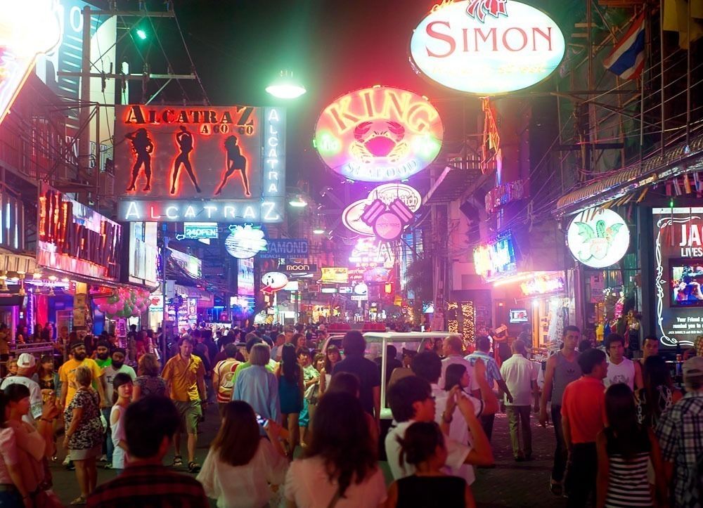 Movimento noturno intenso na Walking Street de Pattaya, com letreiros coloridos e multidão.