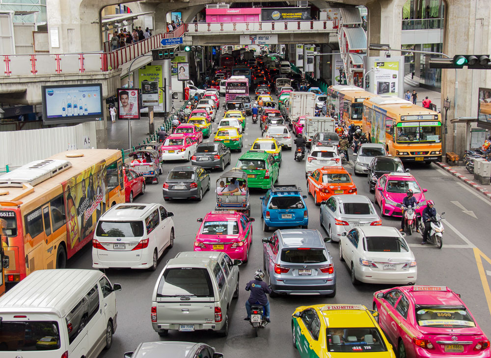 Engarrafamento intenso no centro de Bangkok com táxis coloridos e ônibus.