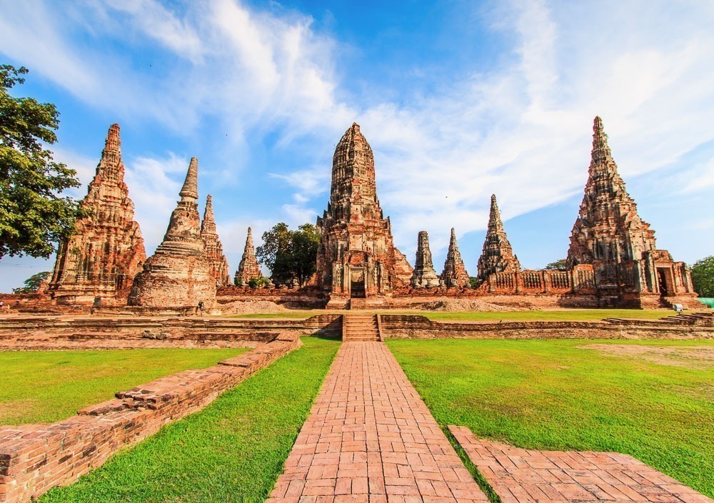 Ruínas do Wat Chaiwatthanaram, em Ayutthaya, com torres simétricas e céu azul ao fundo.