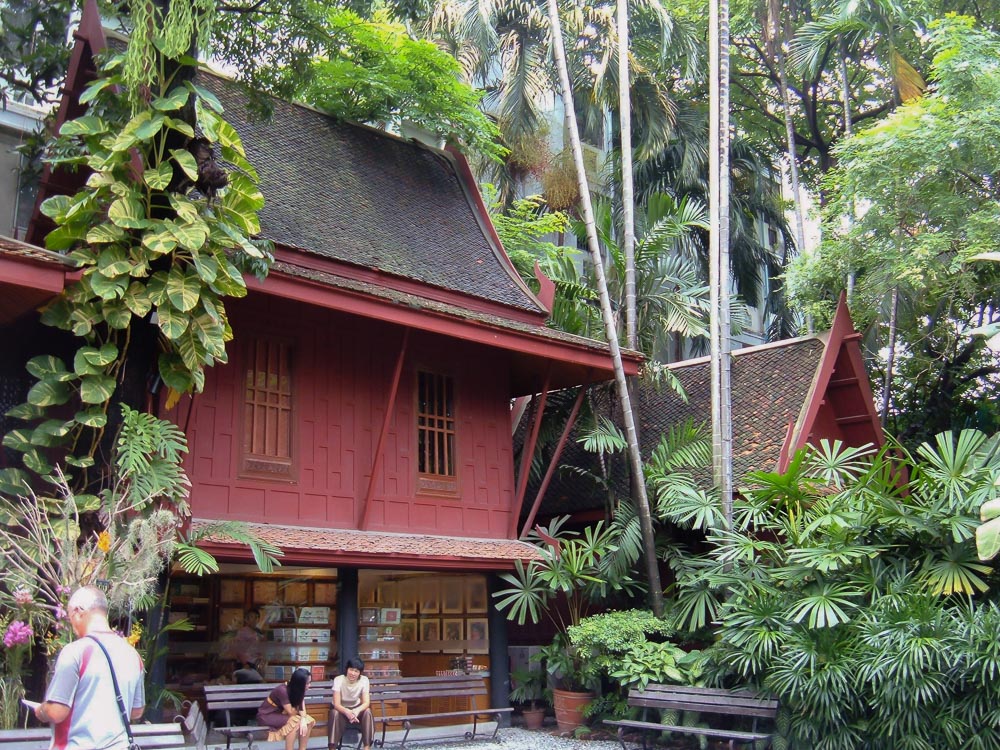 Casa tradicional tailandesa rodeada por vegetação tropical no Museu Jim Thompson.