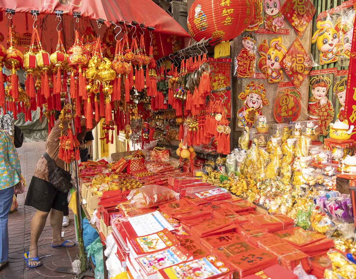 Barraca com decorações vermelhas e douradas típicas do Ano Novo Chinês em um mercado de rua na Tailândia.