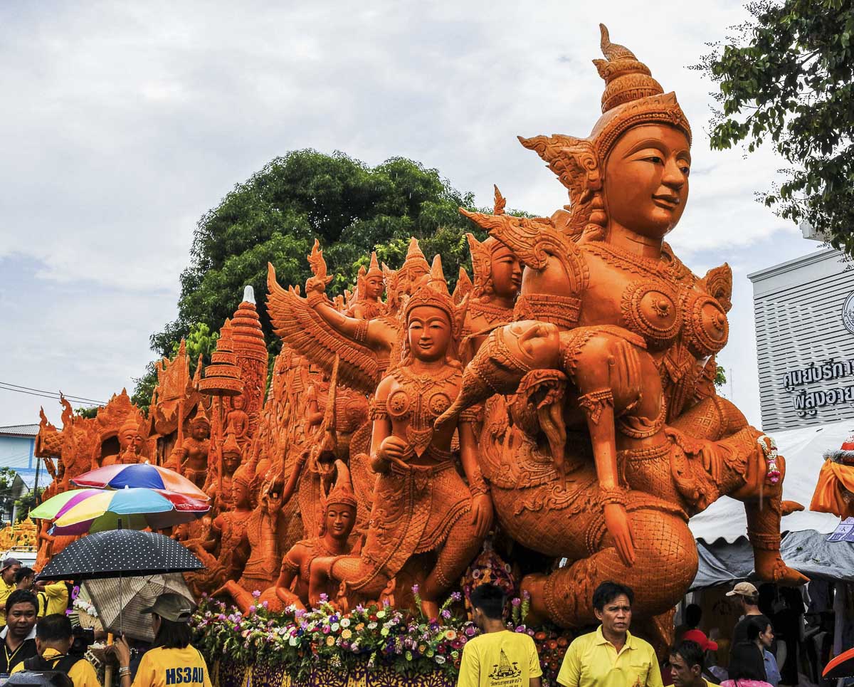 Escultura gigante em cera laranja com figuras mitológicas tailandesas durante o Festival das Velas de Ubon Ratchathani.