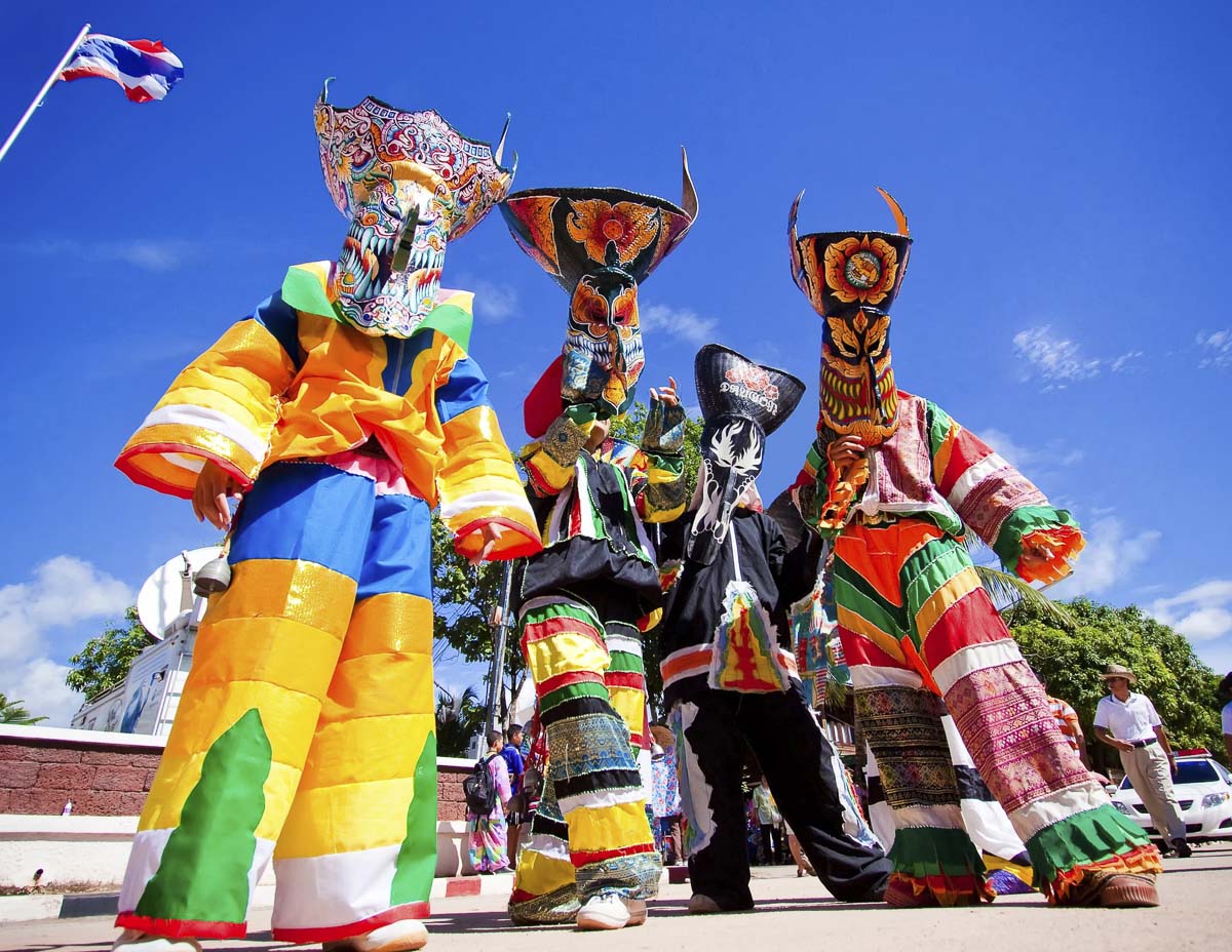 Pessoas com máscaras coloridas e roupas vibrantes durante o Festival dos Fantasmas (Phi Ta Khon), na Tailândia.