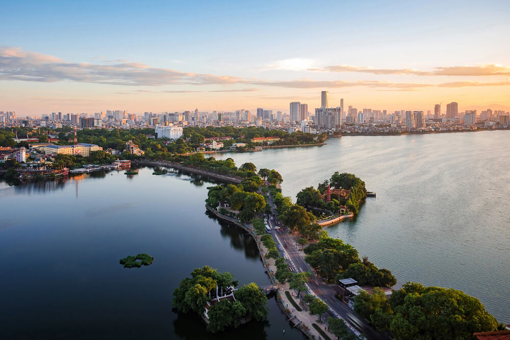 Vista aérea do Lago Oeste em Hanói com a cidade ao fundo ao entardecer.