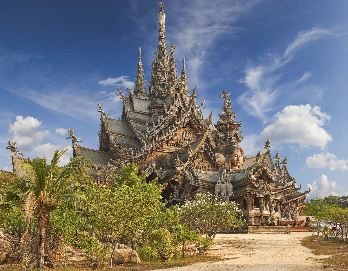 Estrutura de madeira do Santuário da Verdade com esculturas detalhadas e céu azul ao fundo.