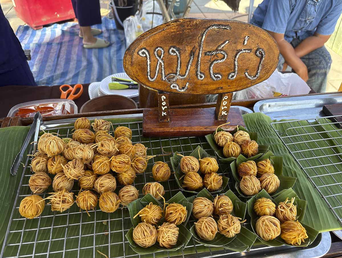 Bolinhos fritos de porco envoltos em fios de macarrão vendidos no mercado Tha Nam Rap Sadet, em Sukhothai.