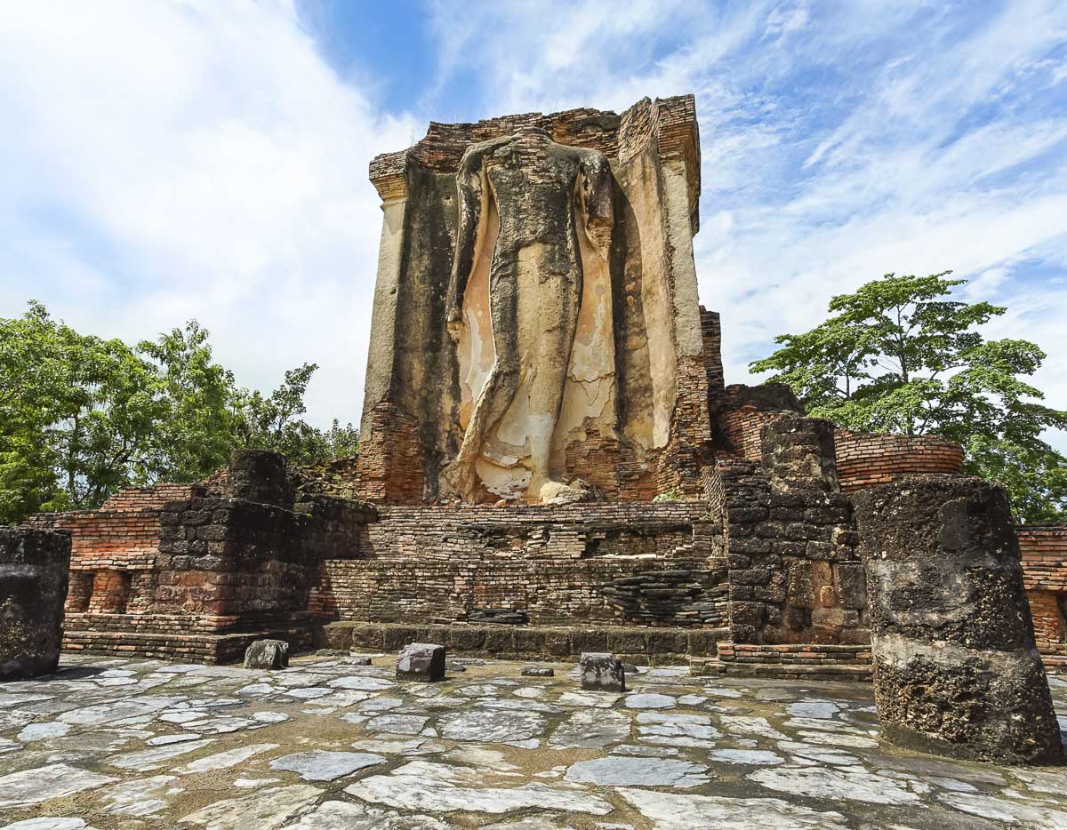 Imagem de Buda em pé entre ruínas antigas no templo Wat Chetuphon, em Sukhothai.