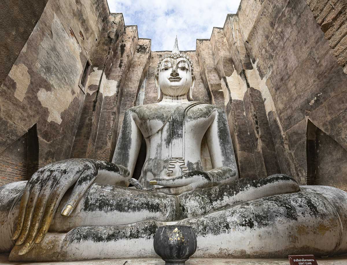 Grande estátua de Buda sentada dentro de uma estrutura de pedra no templo Wat Si Chum, em Sukhothai.