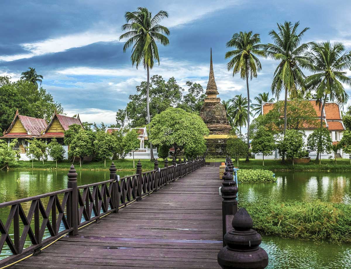 Templo Wat Traphang Thong rodeado por um lago e ligado por uma ponte de madeira, em Sukhothai.
