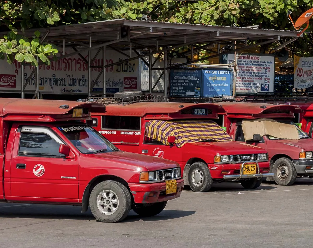 Vários songthaews vermelhos estacionados em uma rua de Chiang Mai, Tailândia.