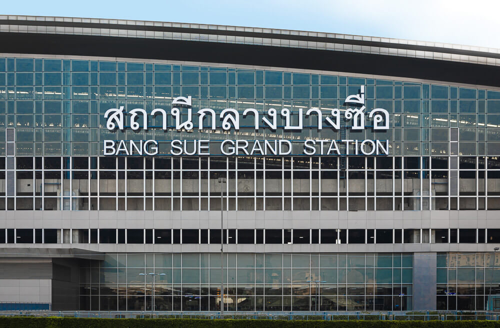Fachada espelhada da moderna estação Bang Sue Grand Station com letreiro em tailandês e inglês.