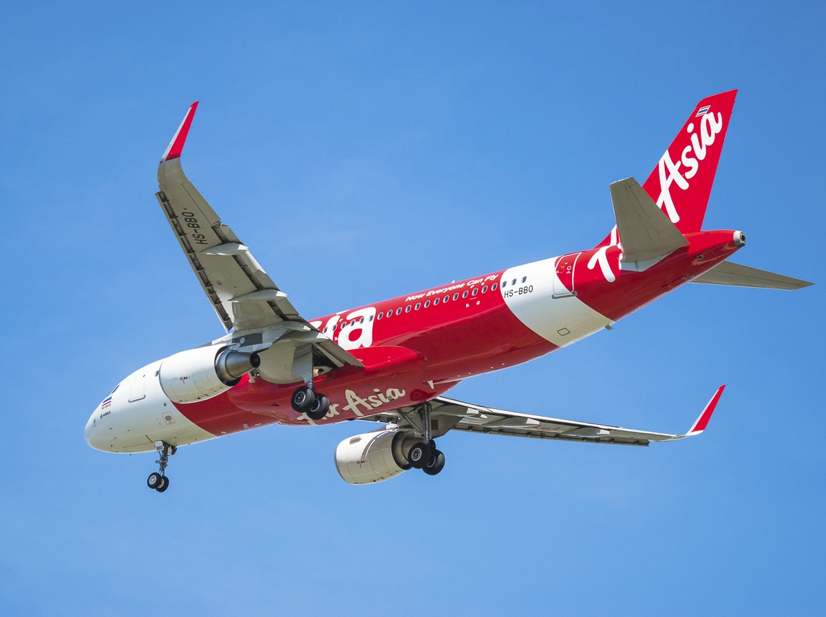 Avião da AirAsia em voo sob céu azul, usado em rotas entre Bangkok e Siem Reap.