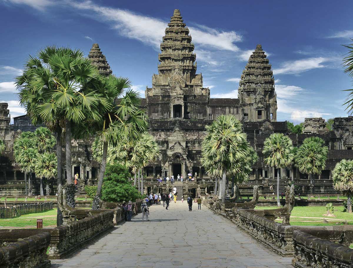 Entrada principal do templo Angkor Wat, em Siem Reap, com turistas caminhando.