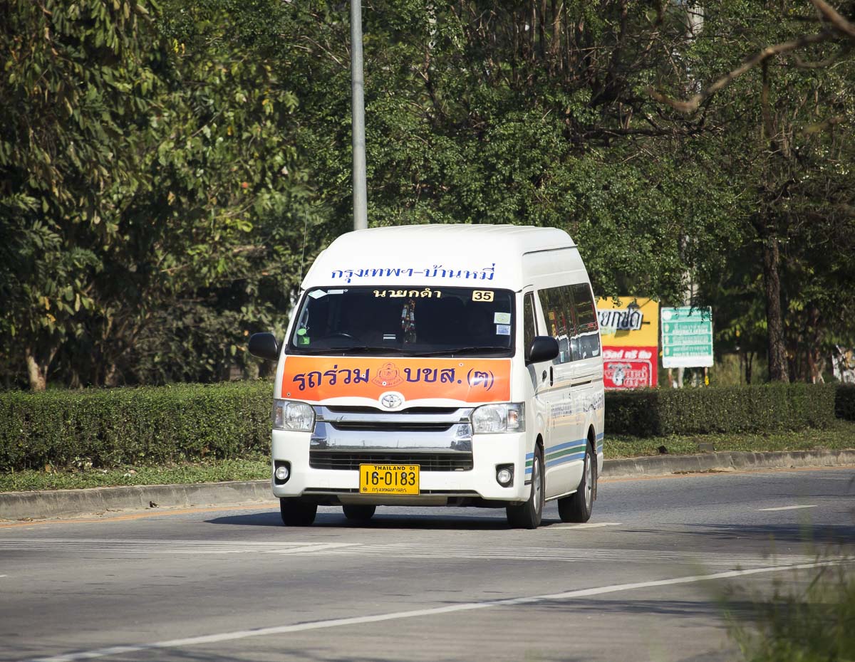 Van de transporte rodando em estrada arborizada na rota entre Tailândia e Camboja.