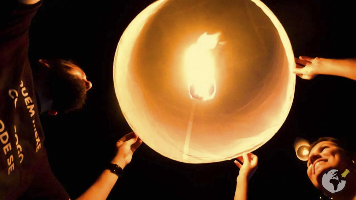 Pessoas segurando uma lanterna de papel iluminada antes de soltá-la no céu durante o Festival das Lanternas na Tailândia.