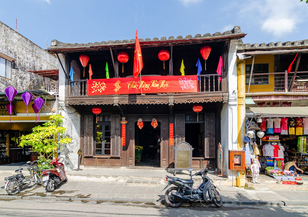 Fachada histórica do Hoi An Museum of Trade Ceramics, casa de madeira com lanternas vermelhas e letreiro festivo.