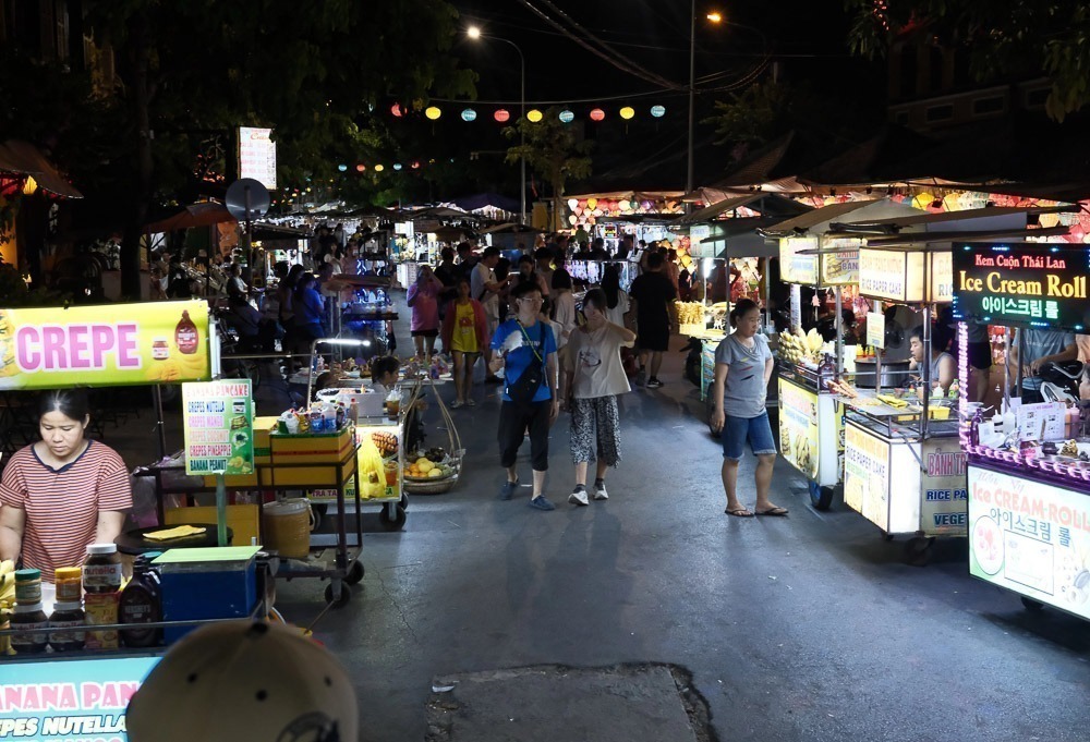 Movimento de visitantes e barracas iluminadas no Night Market de Hoi An.