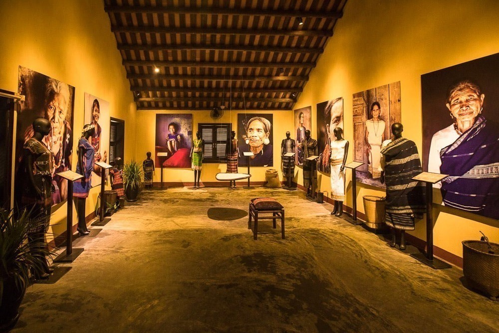 Interior do Precious Heritage Art Gallery Museum em Hoi An, sala com retratos de povos vietnamitas e manequins com trajes tradicionais.