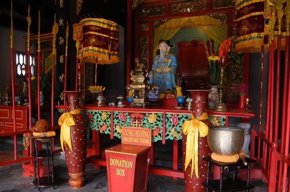 Interior colorido do templo Quan Cong em Hoi An, com altar e estátua dourada do general chinês.