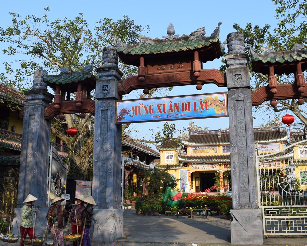 Entrada do templo Pháp Bảo em Hoi An, com portão ornamentado e decoração de Ano Novo Lunar.