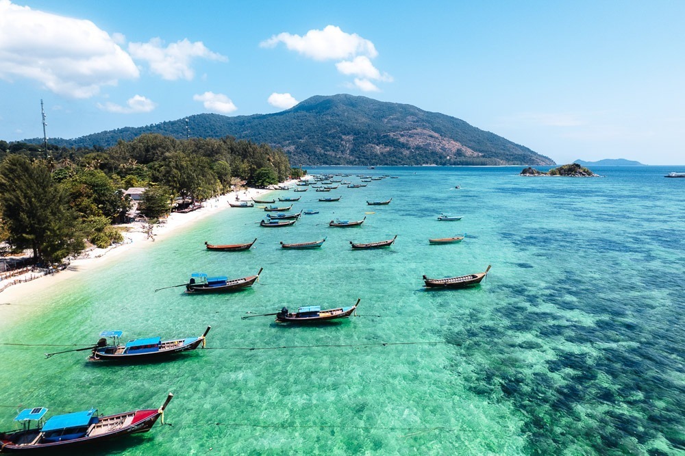 Barcos longtail flutuando sobre águas cristalinas próximas à costa de Koh Lipe.