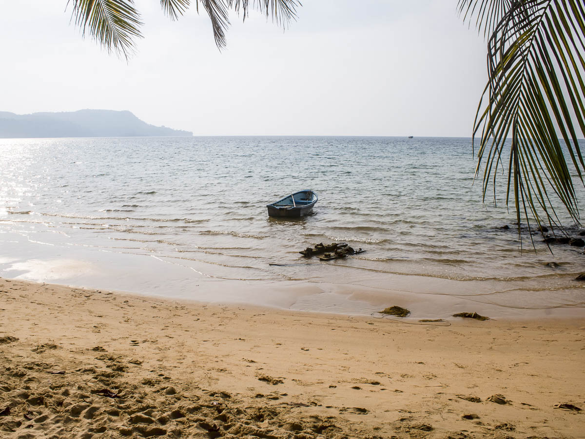 Barco solitário flutuando perto da areia em praia deserta de Koh Rong, Camboja.