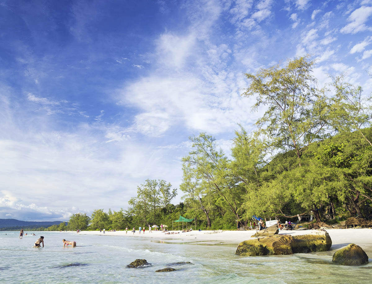 Praia de areia branca e mar cristalino com banhistas em Koh Rong, Camboja.