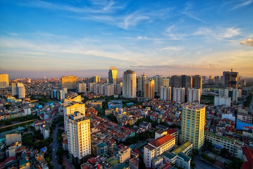 Vista panorâmica do skyline de Hanói ao entardecer, com prédios altos e céu azul.