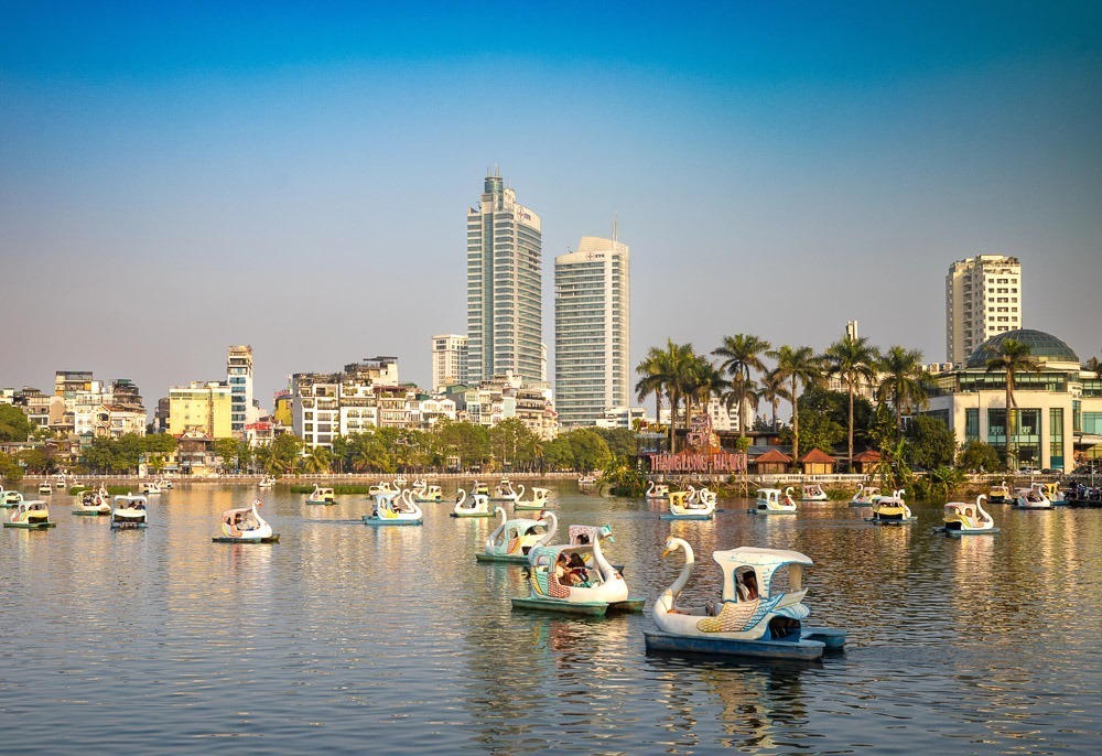 Lago Truc Bach em Hanói, com pedalinhos em formato de cisne e prédios ao fundo.