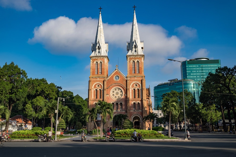 Catedral de Notre Dame de Ho Chi Minh vista de frente, com suas duas torres e fachada em tijolos vermelhos.