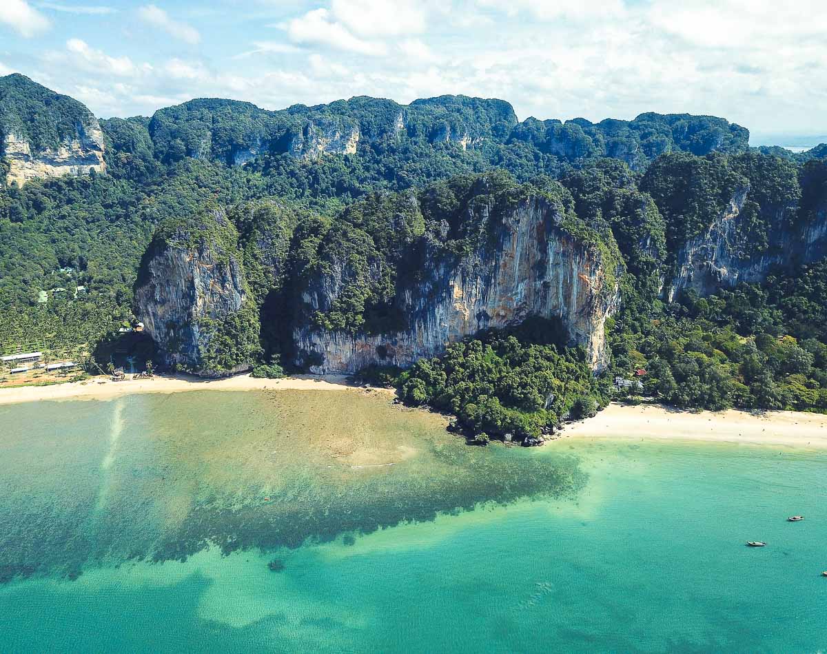 Vista aérea de Railay Beach com paredões calcários, mar azul e mata tropical.