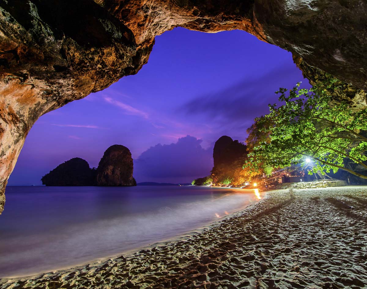 Praia de Railay ao entardecer vista de dentro de uma caverna, com o mar e ilhas ao fundo.