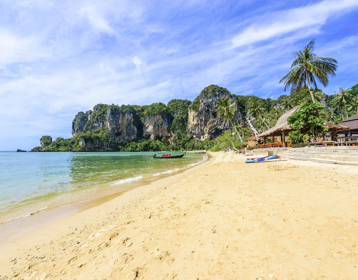Praia de Tonsai com areia dourada, coqueiros e pequenos bares à beira-mar.