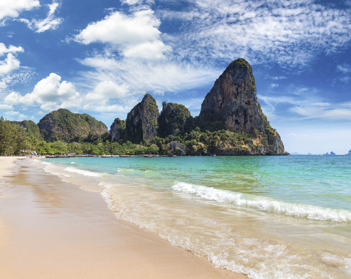 Praia de Railay ao entardecer vista de dentro de uma caverna, com o mar e ilhas ao fundo.