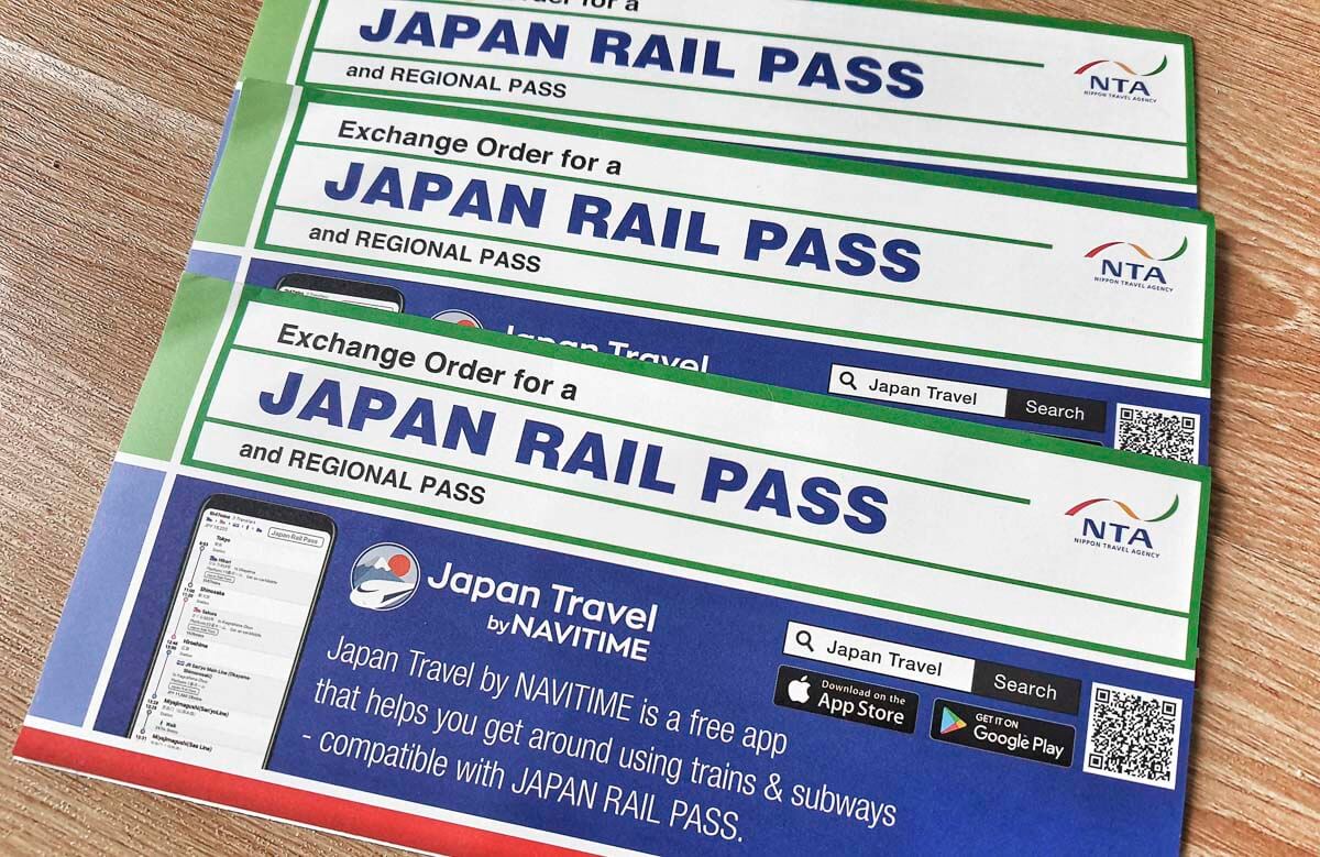 Vouchers do Japan Rail Pass organizados sobre uma mesa de madeira