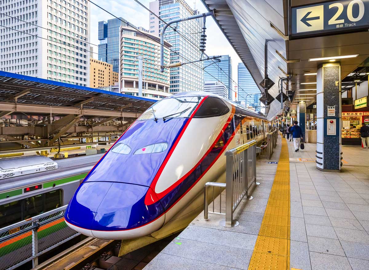 Shinkansen parado na plataforma no Japão, com o trem azul e branco em primeiro plano