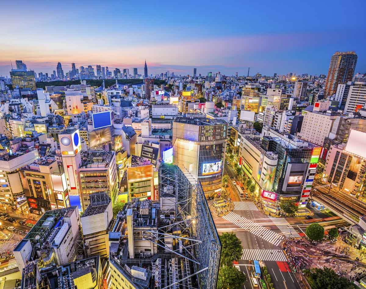Vista aérea de Shibuya com cruzamento famoso, prédios iluminados e movimento intenso